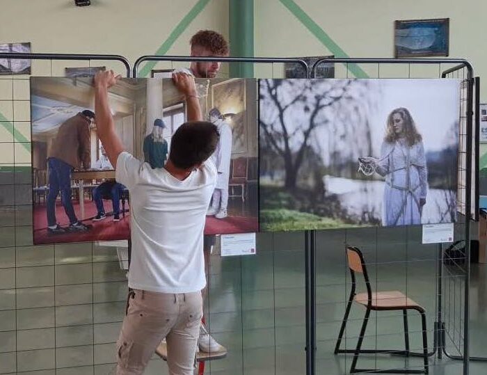 Des jeunes en train d'accrocher sur des grilles les photos imprimées en grand format